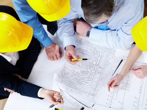 IMAGE: Group of people around plans on a table